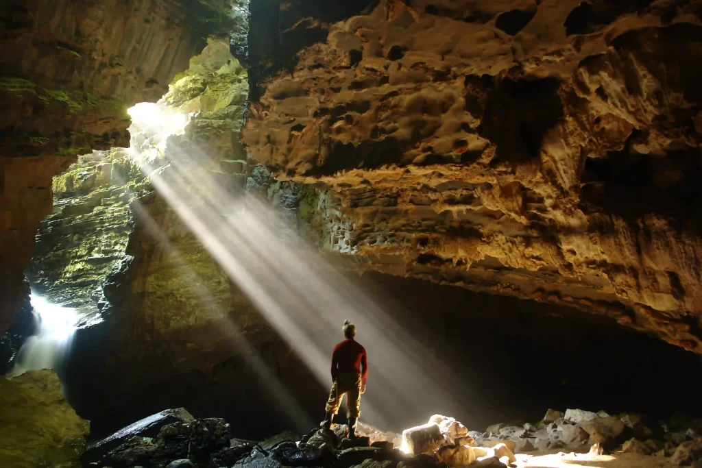 Sunbeam illuminates a person exploring a cave in Intervales State Park, Ribeira Valley
