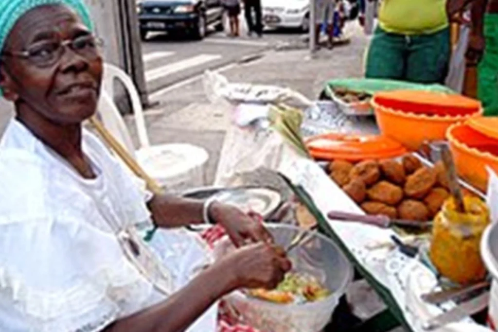 Traditional Baiana in white lace dress serving authentic food on the streets of Salvador, Brazil